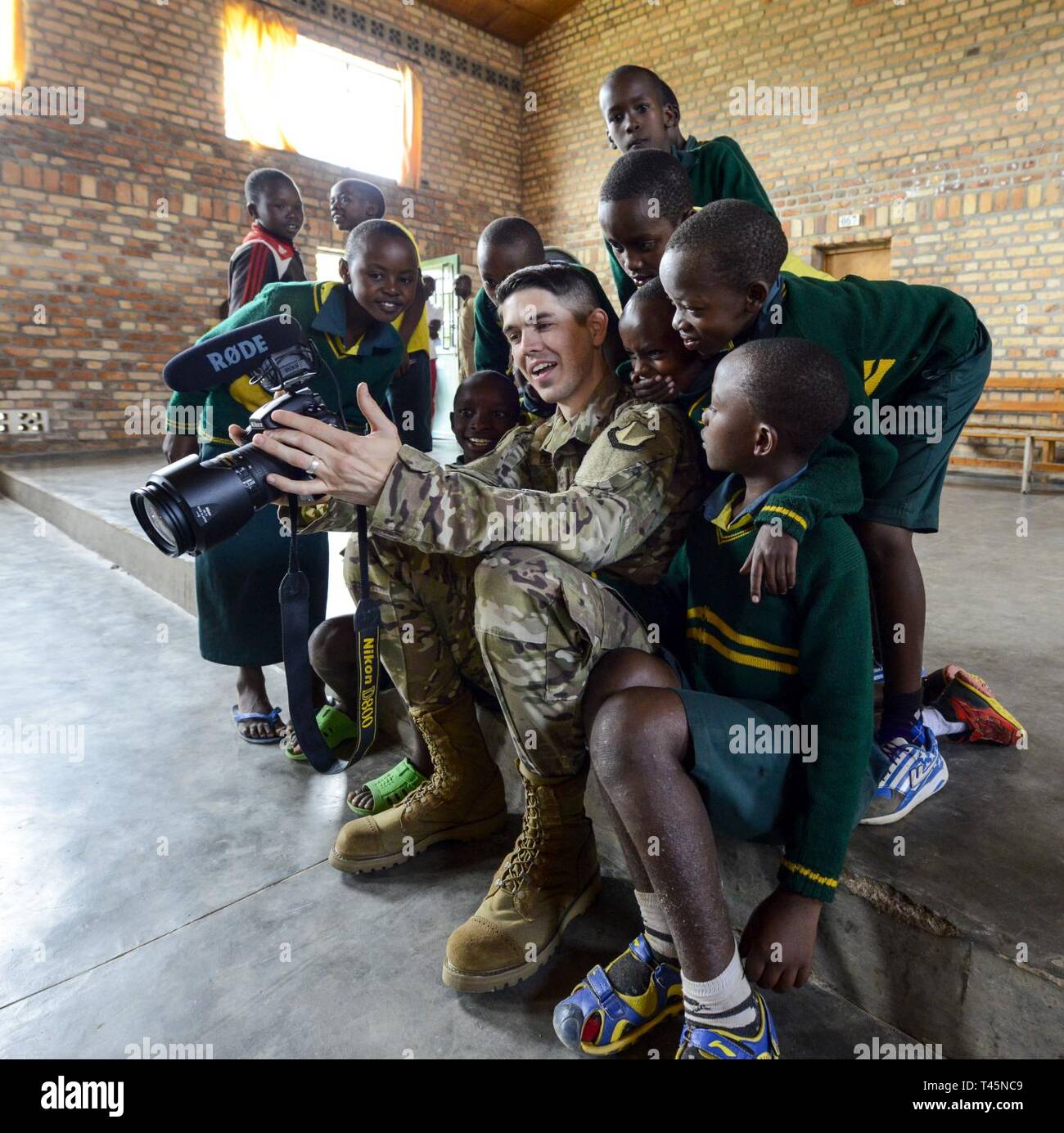 U.S. Air Force Airman 1st Class Noah Coger, a broadcast journalist with the 86th Airlift Wing public affairs office, shows video to some students of the Home de la vierge des Pauvres Gatagara/Nyanza in the Nyanza District, Rwanda, March 5, 2019. Coger traveled to HVP Nyanza with the U.S. Air Forces in Europe Band, who performed a musical concert for the students. Stock Photo