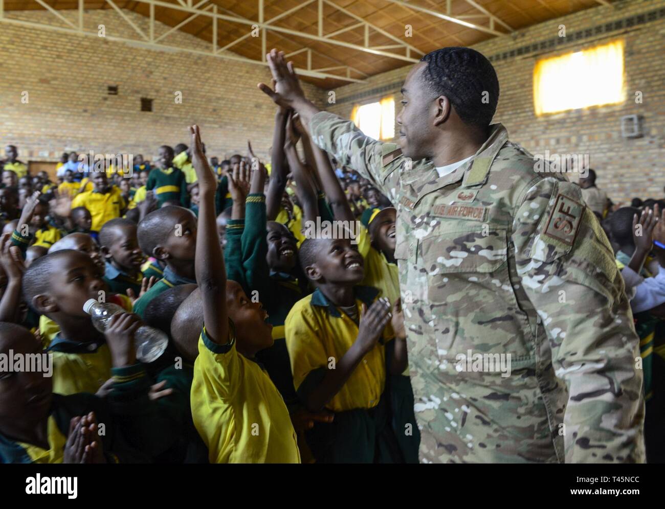 U.S. Air Force Master Sgt. Julius Stokes, Air Force Installation and Mission Support Center Detachment 4, high-fives students of the Home de la vierge des Pauvres Gatagara/Nyanza in the Nyanza District, Rwanda, March 5, 2019. Stokes traveled to HVP Nyanza with the U.S. Air Forces in Europe Band as part of an outreach event. Stock Photo
