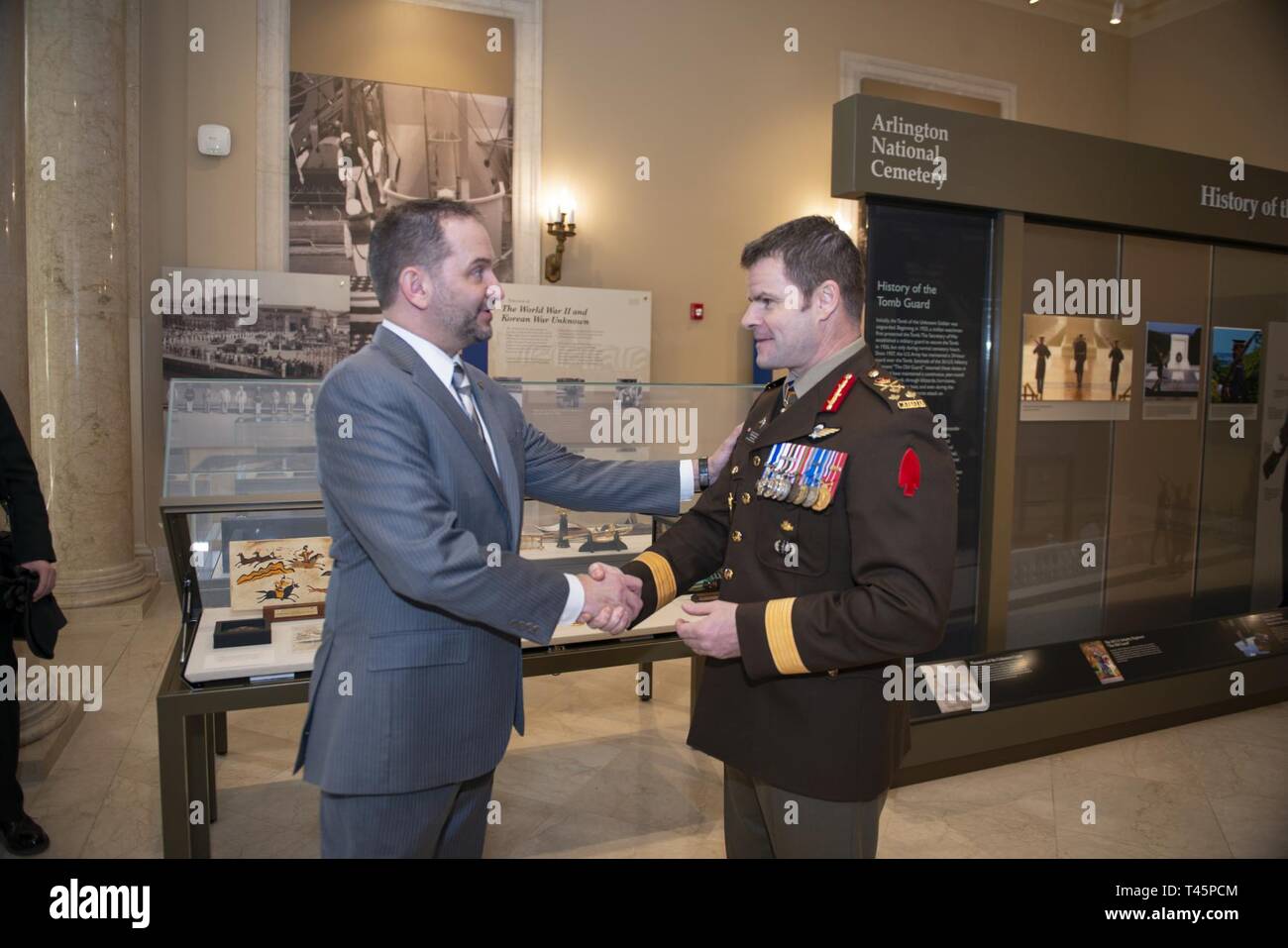 Michael Migliara (left), director of operations, Arlington National Cemetery; presents Lt. Gen. M.N. (Mike) Rouleau (right), commander, Canadian Joint Operations Command; with a coin in the Memorial Amphitheater Display Room at Arlington National Cemetery, Arlington, Virginia, March 6, 2019. While at the cemetery, Rouleau participated in a Public Wreath-Laying Ceremony at the Tomb of the Unknown Soldier and observed the Changing of the Guard. Stock Photo