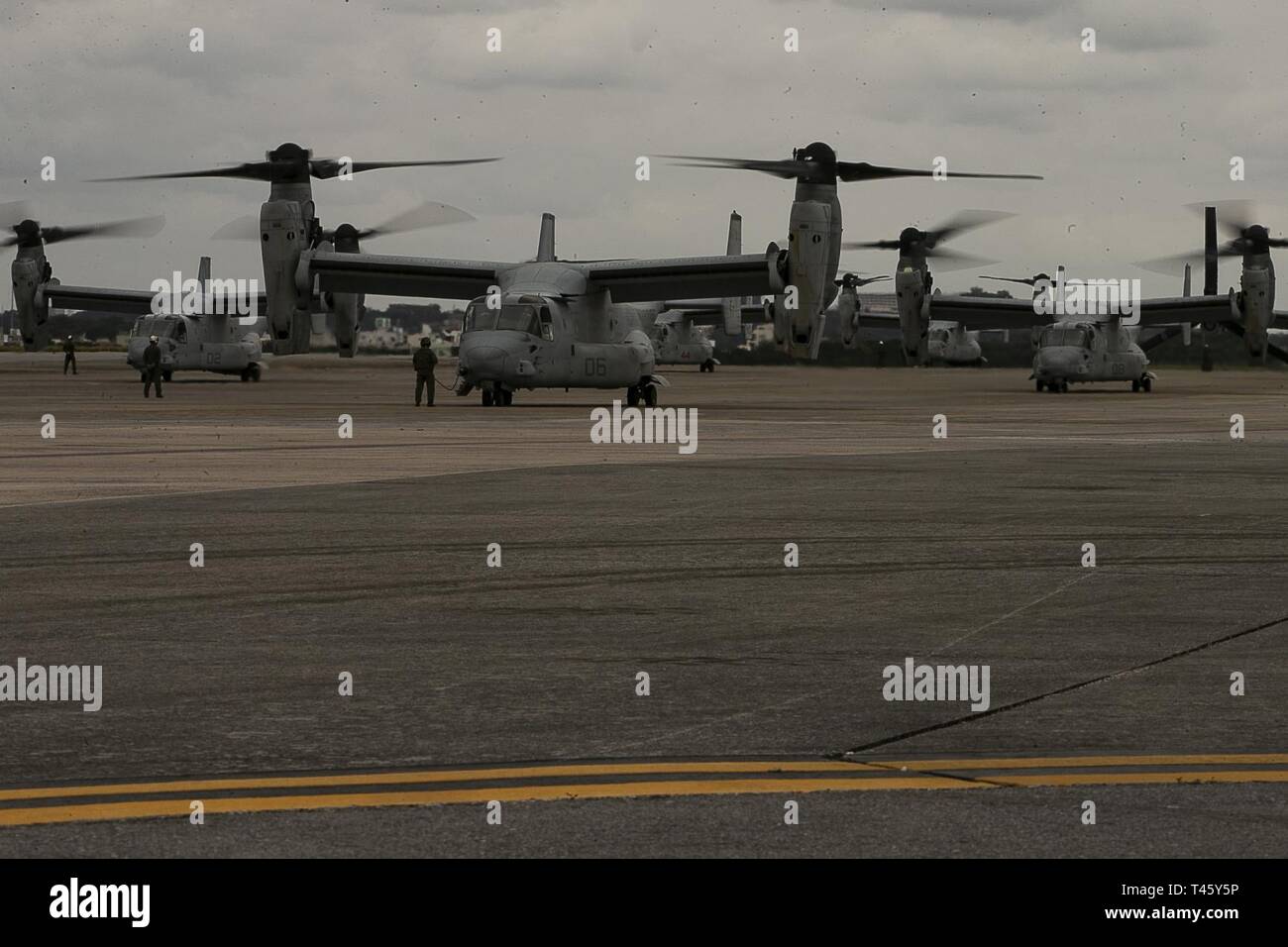 MV-22B Osprey tiltrotor aircraft belonging to Marine Medium Tiltrotor Squadron 262 (Reinforced) idle before flight atop the flight line at Marine Corps Air Station Futenma, Okinawa, Japan, March 11, 2019. VMM-262 (Rein.) is the Aviation Combat Element for the 31st Marine Expeditionary Unit. Marines with the 31st MEU are conducting simulated EABO in a series of dynamic training events to refine their ability to plan, rehearse and complete a variety of missions. During EABO, the 31st MEU partnered with the 3rd Marine Division, 3rd Marine Logistics Group and 1st Marine Aircraft Wing, and airmen w Stock Photo