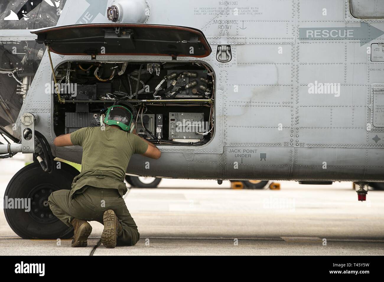 A Marine with Marine Medium Tiltrotor Squadron 262 (Reinforced) performs maintenance on a CH-53E Super Stallion helicopter outside the squadron’s hangar at Marine Corps Air Station Futenma, Okinawa, Japan, March 11, 2019. VMM-262 (Rein.) is the Aviation Combat Element for the 31st Marine Expeditionary Unit. Marines with the 31st MEU are conducting simulated EABO in a series of dynamic training events to refine their ability to plan, rehearse and complete a variety of missions. During EABO, the 31st MEU partnered with the 3rd Marine Division, 3rd Marine Logistics Group and 1st Marine Aircraft W Stock Photo
