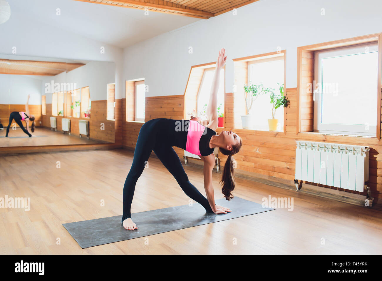 Young attractive woman practicing yoga, standing in Revolved Triangle ...