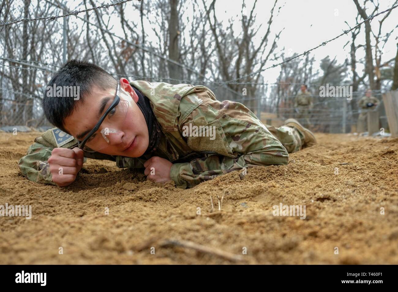 Pfc. Hyunmean Mo, Korean Augmentation to the U.S. Army (KATUSA) automated logistical specialist, Battery B., 3rd Battalion, 13th Field Artillery Regiment, 75th Field Artillery Brigade (FAB),  low crawls through the belly crawl obstacle during the 210th FAB 2019 Best Warrior Competition, Camp Hovey, Republic of Korea, March 12, 2019. The competition served as a valuable training experience, and the winners will advance to the 2nd Infantry Division Best Warrior Competition April 2019. Stock Photo