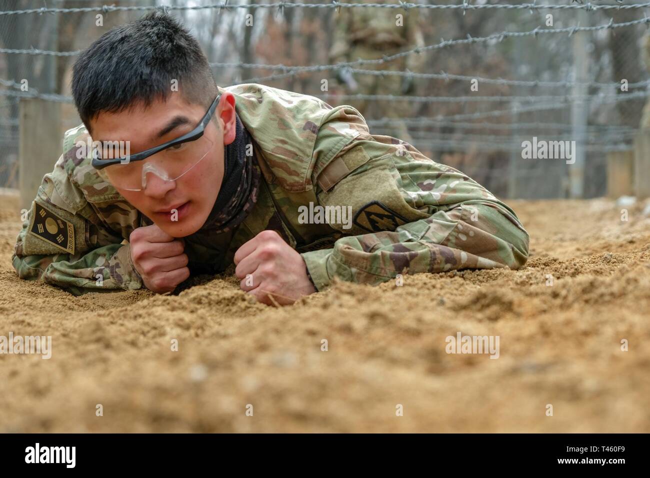 Pfc. Hyunmean Mo, Korean Augmentation to the U.S. Army (KATUSA) automated logistical specialist, Battery B., 3rd Battalion, 13th Field Artillery Regiment, 75th Field Artillery Brigade (FAB), crawls through the low belly crawl obstacle during the obstacle course event as part of the 210th FAB 2019 Best Warrior Competition, Camp Hovey, Republic of Korea, March 12, 2019. The competition served as a valuable training experience, and the winners will advance to the 2nd Infantry Division Best Warrior Competition April 2019. Stock Photo