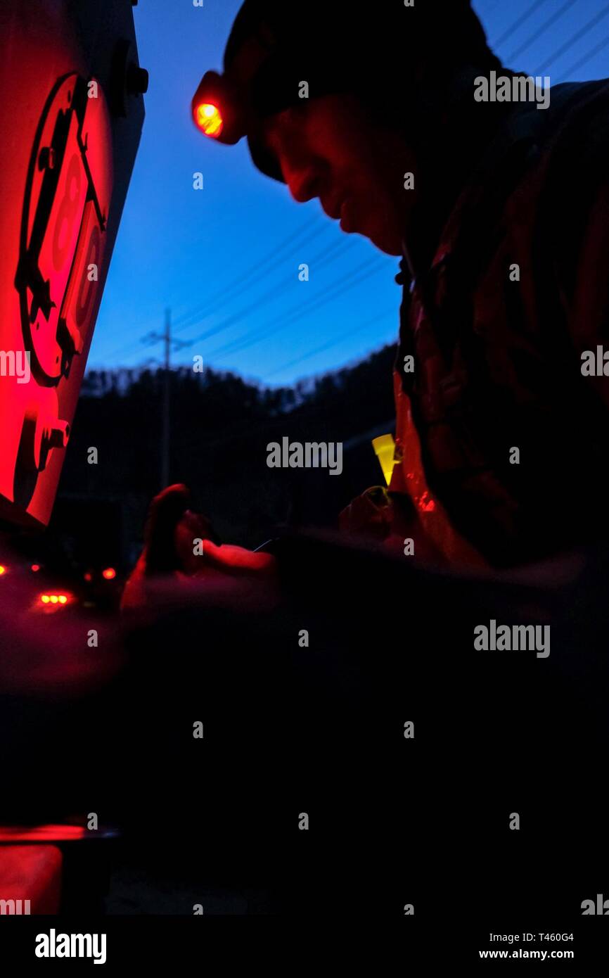 Sgt. 1st Class Cody Dickson, multiple launch rocket system (MLRS/HIMARS) crewmember, assigned to Battery B., 3rd Battalion, 13th Field Artillery Regiment, 75th Field Artillery Brigade (FAB), uses a red lens headlamp to plot points prior to nighttime land navigation during the 210th FAB 2019 Best Warrior Competition, Camp Casey, Republic of Korea, March 12, 2019. The competition served as a valuable training experience, and the winners will advance to the 2nd Infantry Division Best Warrior Competition April 2019. Stock Photo