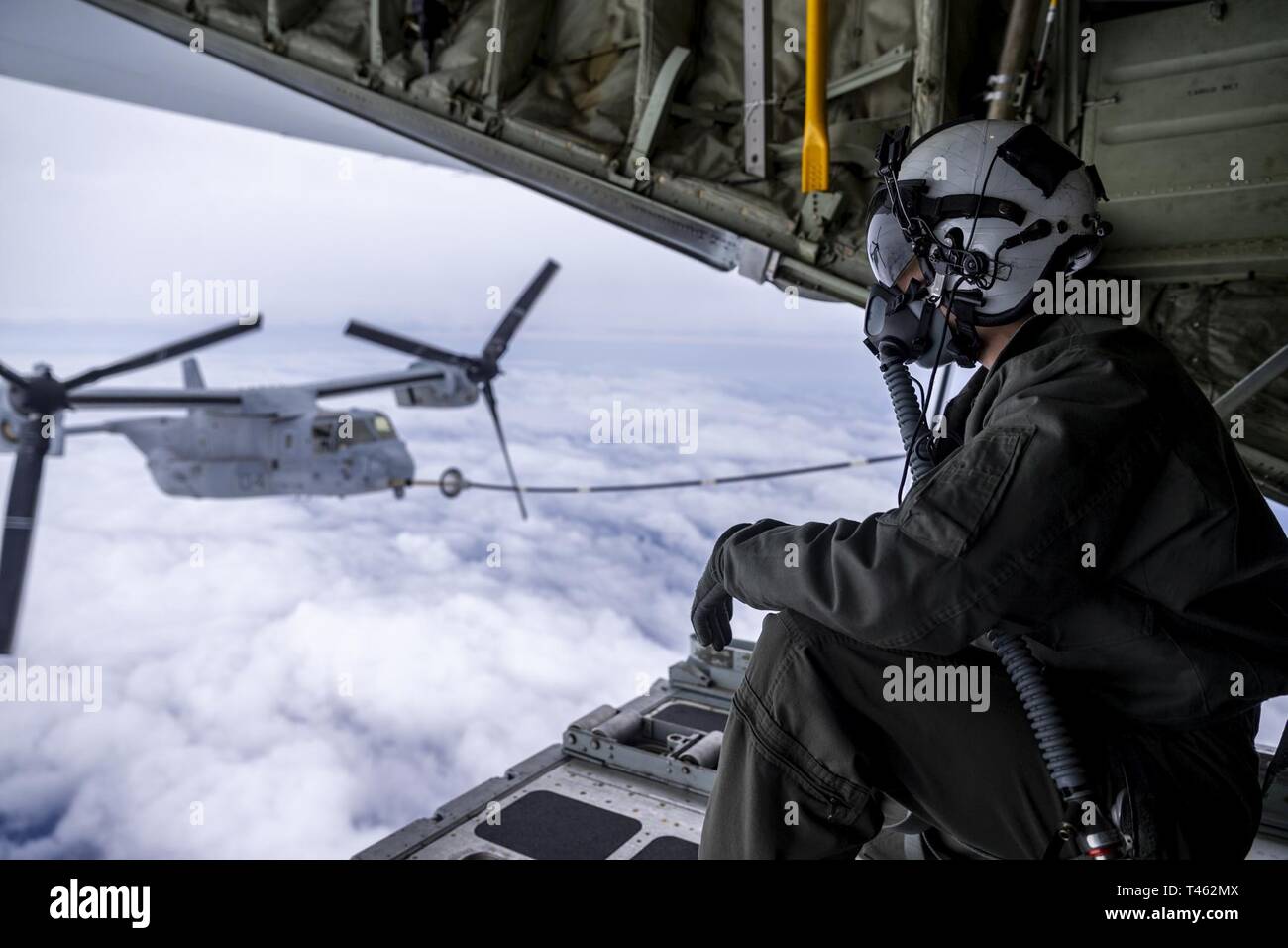 U.S. Marine Corps Cpl. Jack Bourgeois, a KC-130J Super Hercules crewmaster with Marine Aerial Refueler Transport Squadron (VMGR) 152, observes an MV-22B Osprey tiltrotor aircraft belonging to Marine Medium Tiltrotor Squadron 262 (Reinforced) off the coast of Japan, Feb. 28, 2019. U.S. Marines with VMGR-152 provide a wide range of capabilities throughout the INDOPACOM area to include aerial refueling, personnel and cargo transportation, and aerial delivery. Stock Photo