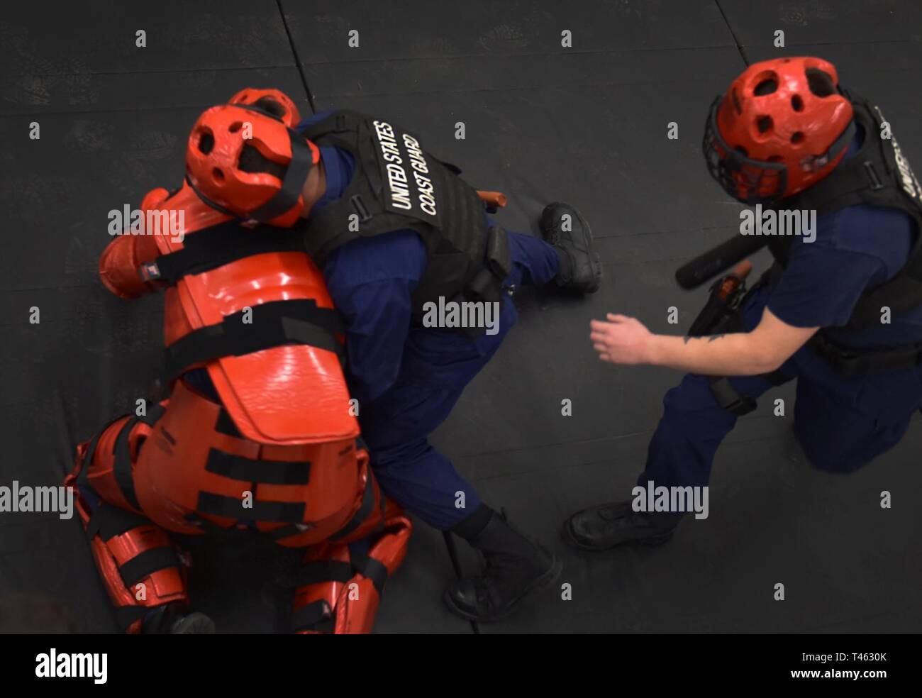 Coast Guard members practice takedown and handcuff techniques while