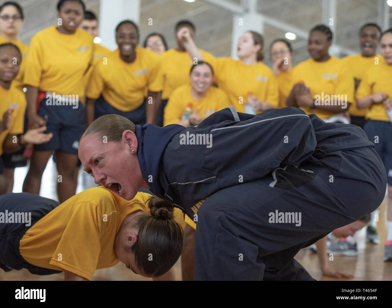 GREAT LAKES, Ill. (Mar. 2, 2019) Chief Aviation Machinist's Mate Sabrina Mayo, a recruit division commander, motivates recruits as they compete in a push-up contest inside Freedom Hall at Recruit Training Command. Recruit divisions compete against each other in 10 different fitness events to earn the Captain's Cup and the opportunity to display the Captain's Cup flag at their pass-in-review graduation ceremony. More than 30,000 recruits graduate annually from the Navy's only boot camp. Stock Photo