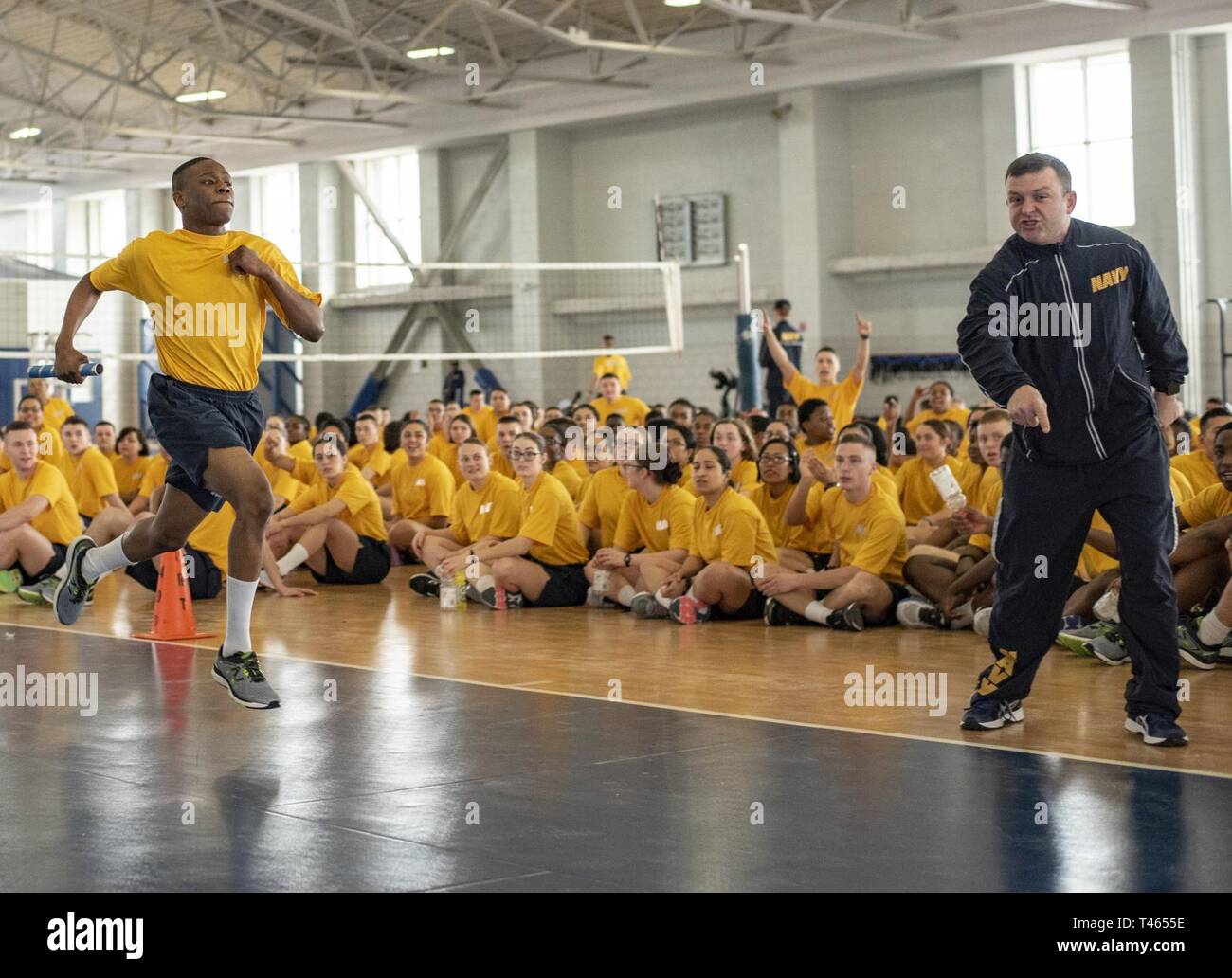 GREAT LAKES, Ill. (Mar. 2, 2019) A recruit division commander motivates a recruit as he competes in a 1.5-mile relay inside Freedom Hall at Recruit Training Command. Recruit divisions compete against each other in 10 different fitness events to earn the Captain's Cup and the opportunity to display the Captain's Cup flag at their pass-in-review graduation ceremony. More than 30,000 recruits graduate annually from the Navy's only boot camp. Stock Photo