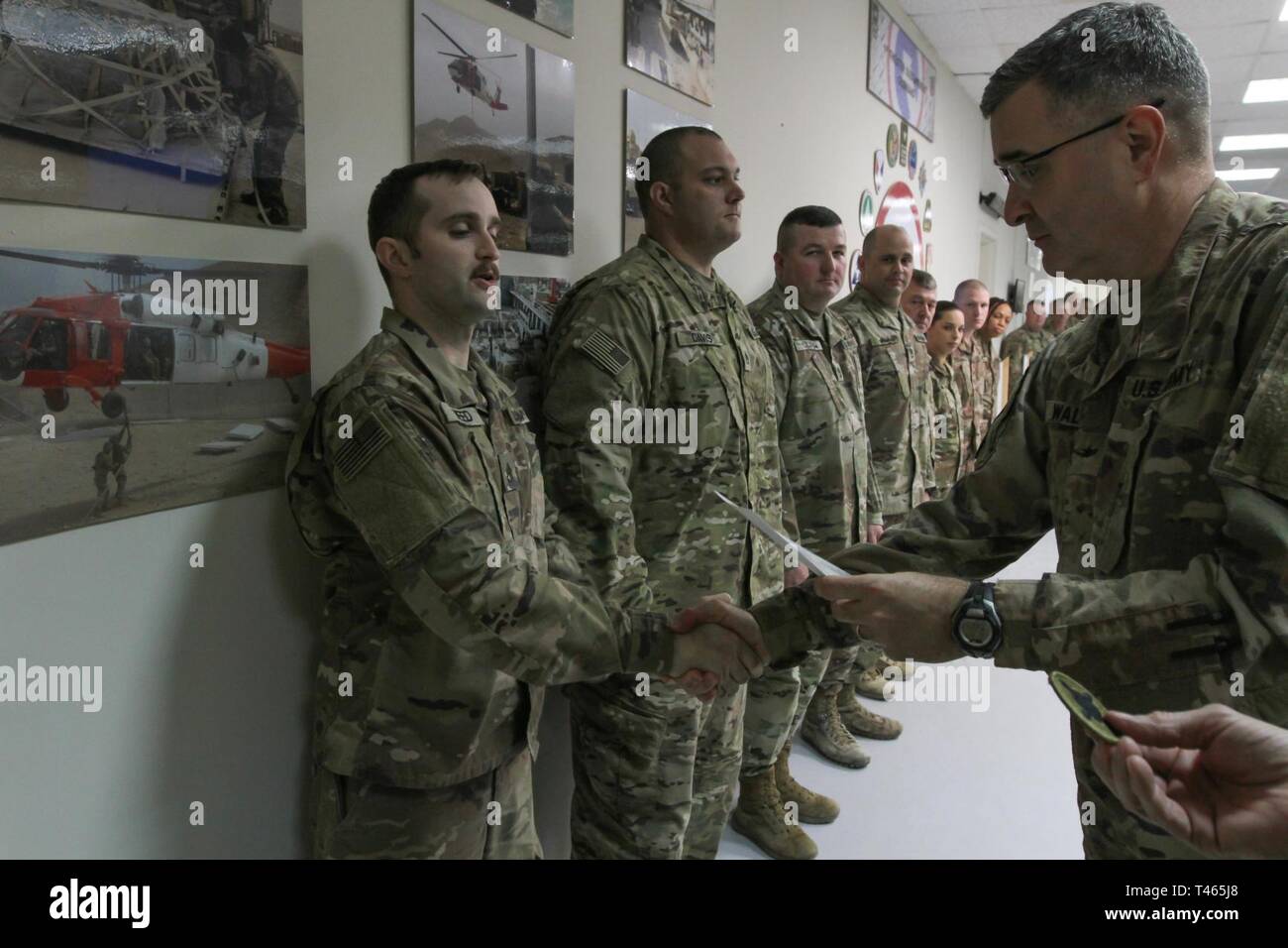 Brig. Gen. Clint E. Walker, commanding general of the 184th Sustainment Command, presents a certificate of wartime service to Staff Sgt. Kelcy Weed following the placement of the 184th ESC patch on his right shoulder at Camp Arifjan, Kuwait, Mar. 3, 2019. Stock Photo