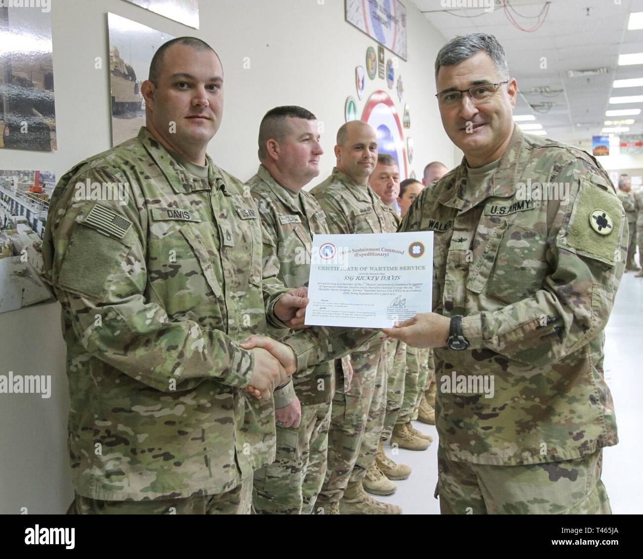 Brig. Gen. Clint E. Walker, commanding general of the 184th Sustainment Command, presents a certificate of wartime service to  Staff Sgt. Rickey Davis following the placement of the 184th ESC patch on his right shoulder at Camp Arifjan, Kuwait, Mar. 3, 2019. Stock Photo