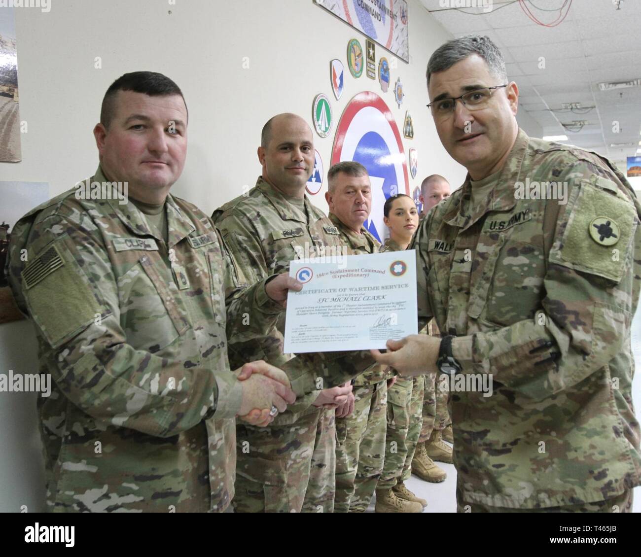 Brig. Gen. Clint E. Walker, commanding general of the 184th Sustainment Command, presents a certificate of wartime service to Sgt. 1st class Michael Clark following the placement of the 184th ESC patch on his right shoulder at Camp Arifjan, Kuwait, Mar. 3, 2019. Stock Photo