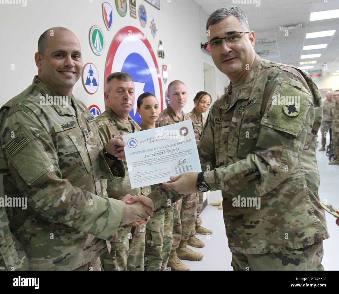 Brig. Gen. Clint E. Walker, commanding general of the 184th Sustainment Command, presents a certificate of wartime service to Sgt. 1st class Benjamin Fisk following the placement of the 184th ESC patch on his right shoulder at Camp Arifjan, Kuwait, Mar. 3, 2019. Stock Photo
