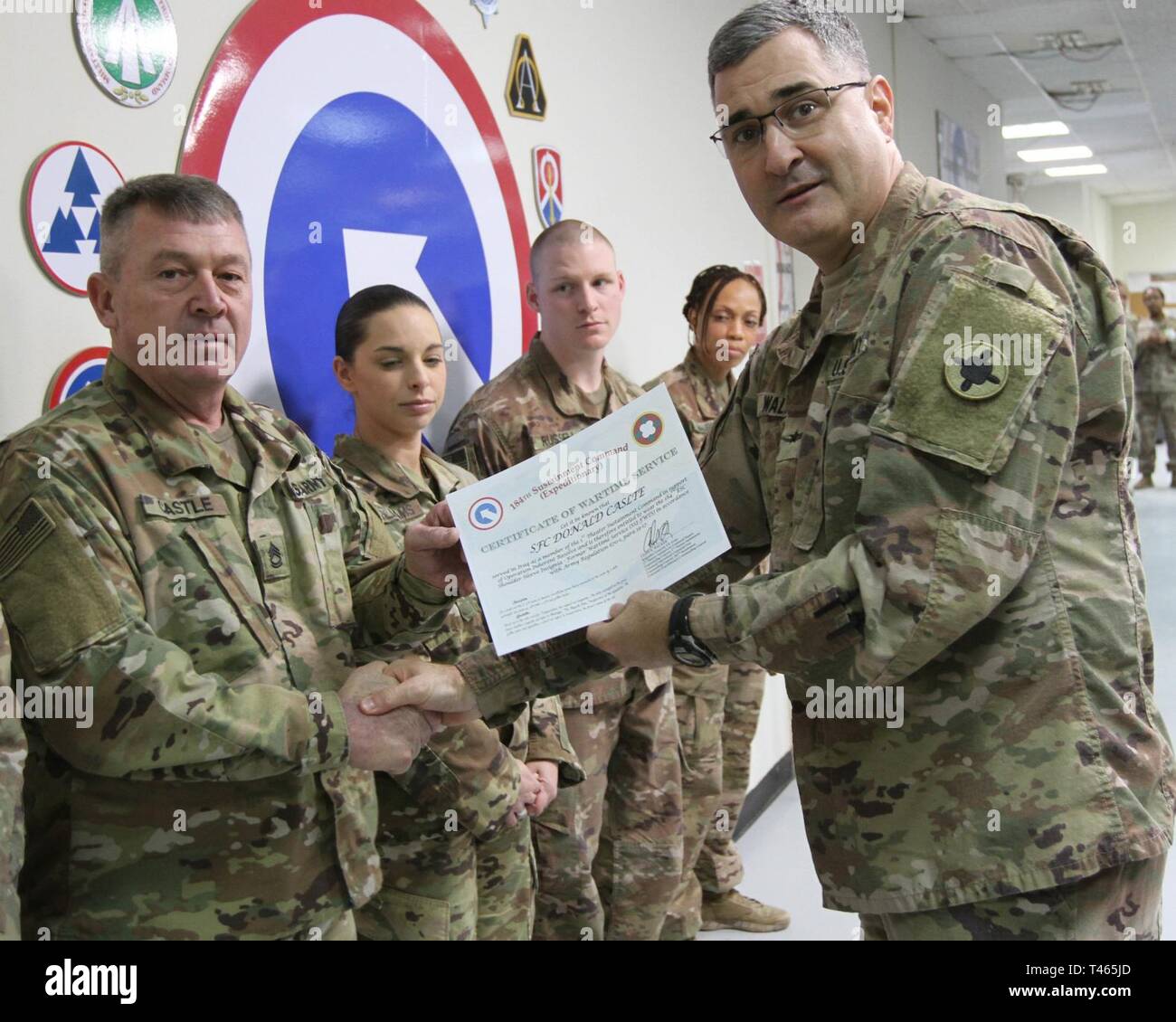Brig. Gen. Clint E. Walker, commanding general of the 184th Sustainment Command, presents a certificate of wartime service to Sgt. 1st Class Donald Castle following the placement of the 184th ESC patch on his right shoulder at Camp Arifjan, Kuwait, Mar. 3, 2019. Stock Photo