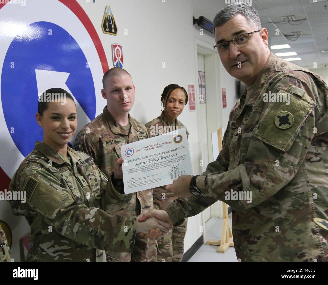 Brig. Gen. Clint E. Walker, commanding general of the 184th Sustainment Command, presents a certificate of wartime service to Sgt. Heather Williams following the placement of the 184th ESC patch on his right shoulder at Camp Arifjan, Kuwait, Mar. 3, 2019. Stock Photo