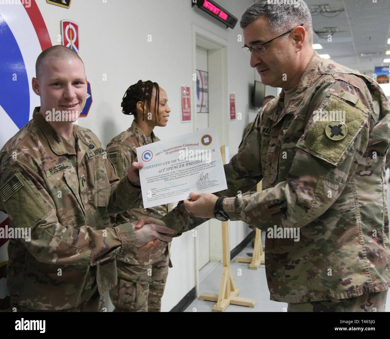 Brig. Gen. Clint E. Walker, commanding general of the 184th Sustainment Command, presents a certificate of wartime service to 1st Lt. Spencer Russell following the placement of the 184th ESC patch on his right shoulder at Camp Arifjan, Kuwait, Mar. 3, 2019. Stock Photo