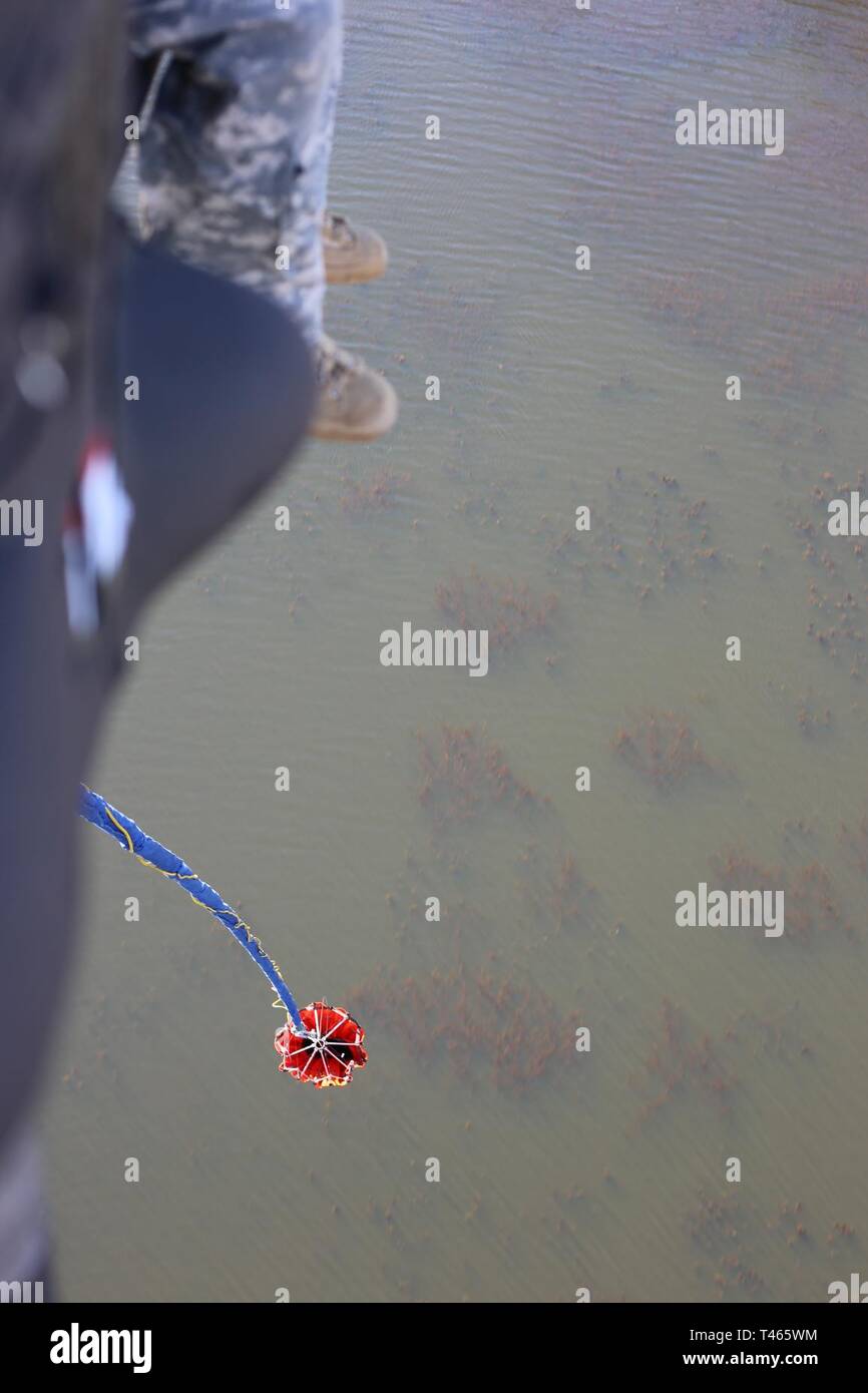 A crew chief on a Blackhawk helicopter watches the water bucket pendent during a check ride with the US Forest Service, as it approaches the water for pickup. Stock Photo