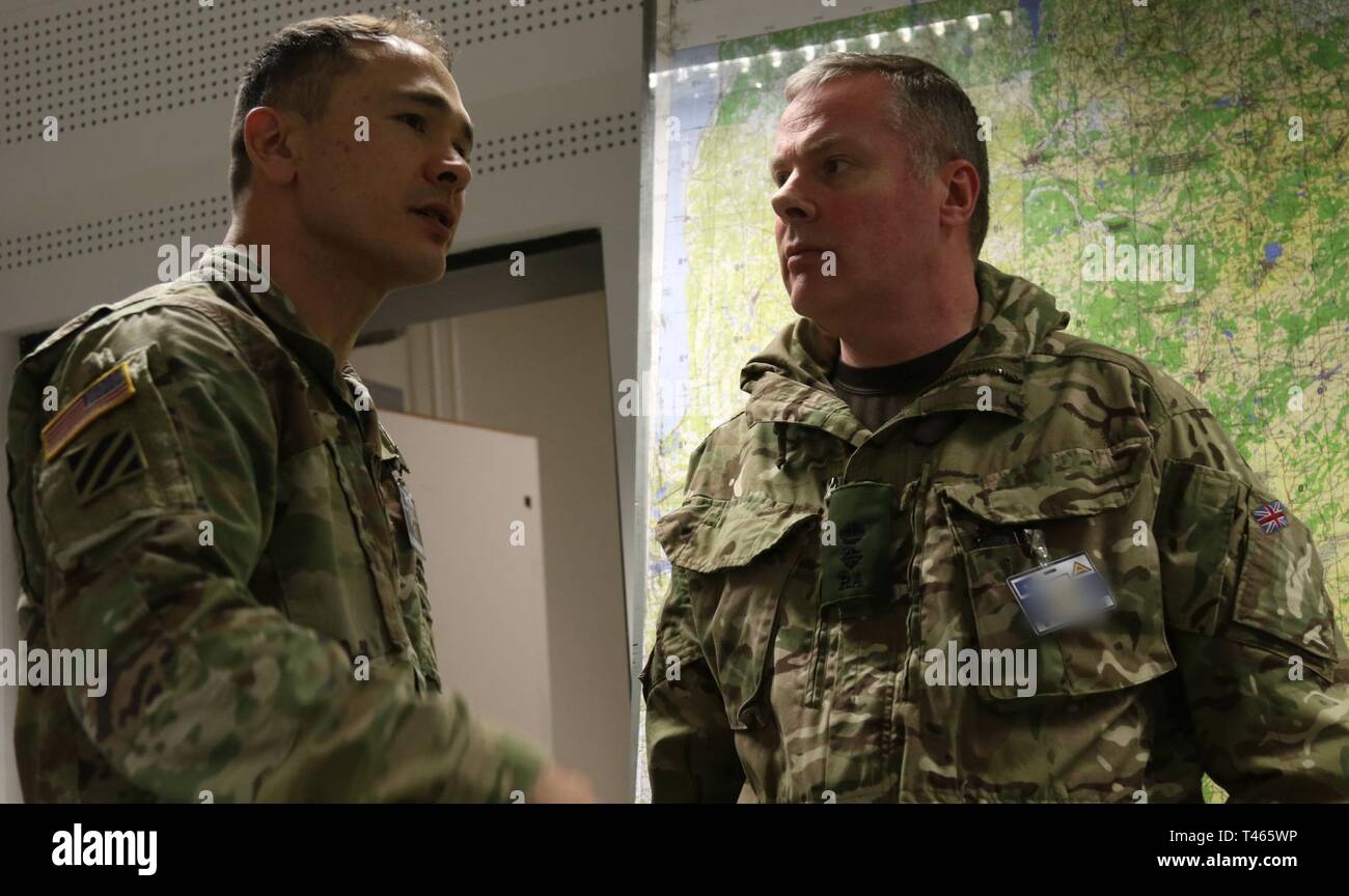 Lt. Col. Eric Gust (left), a staff officer with Headquarters, Allied Rapid Reaction Corps, shares strategic ideas with British Army Lt. Col. Tim Iddon (right), chief of operations with ARRC during exercise Dynamic Front 19, March 5 at Grafenwoehr Training Area, Germany. Dynamic Front 19 is a multinational exercise conducted by the U.S. Army in Europe designed to improve allied and partner nation ability to deliver long-range fire capabilities. It allows Allies to connect personally, professionally, technically and tactically to create stronger and more capable forces in time of crisis. Stock Photo