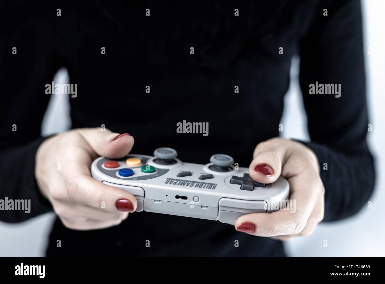 HEGGENES, NORWAY - FEBRUARY 6, 2019: Closeup of woman holding a gaming controller with Super Nintendo retro design playing video games Stock Photo
