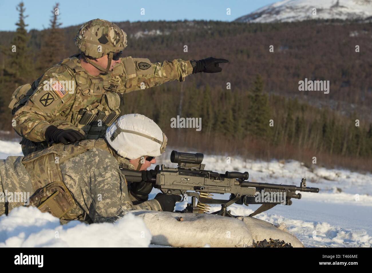 Army Sgt. James Cascio, top, directs Sgt. Trenton Fussell’s fire during M240L machine gun during live-fire training at Grezelka range, Joint Base Elmendorf-Richardson, Alaska, March 4, 2019. Utilizing the M249 light machine gun and M240L machine gun, Spartan paratroopers assigned to Blackfoot Company, 1st Battalion, 501st Parachute Infantry Regiment, 4th Infantry Brigade Combat Team (Airborne), 25th Infantry Division, U.S. Army Alaska, honed their marksmanship skills by engaging multiple targets at varying distances. Stock Photo