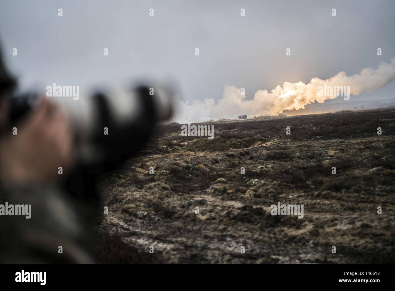 U.S. Marine Corps Sgt. Andy O. Martinez, a mass communicator with Marine Forces Reserve’s Communication Strategy and Operations section, photographs a High Mobility Artillery Rocket System fire a rocket during live-fire range at Adazi Training Area, Latvia, March 4, 2019, during exercise Dynamic Front 19. Two HIMARS from Fox Battery, 2nd Battalion, 14th Marine Regiment, 4th Marine Division, coordinated fires with army units in Germany. Approximately 3,200 participants from 27 nations will take part in the live-fire portion of exercise Dynamic Front 19, March 2-9, 2019, at the U.S. Army's Grafe Stock Photo