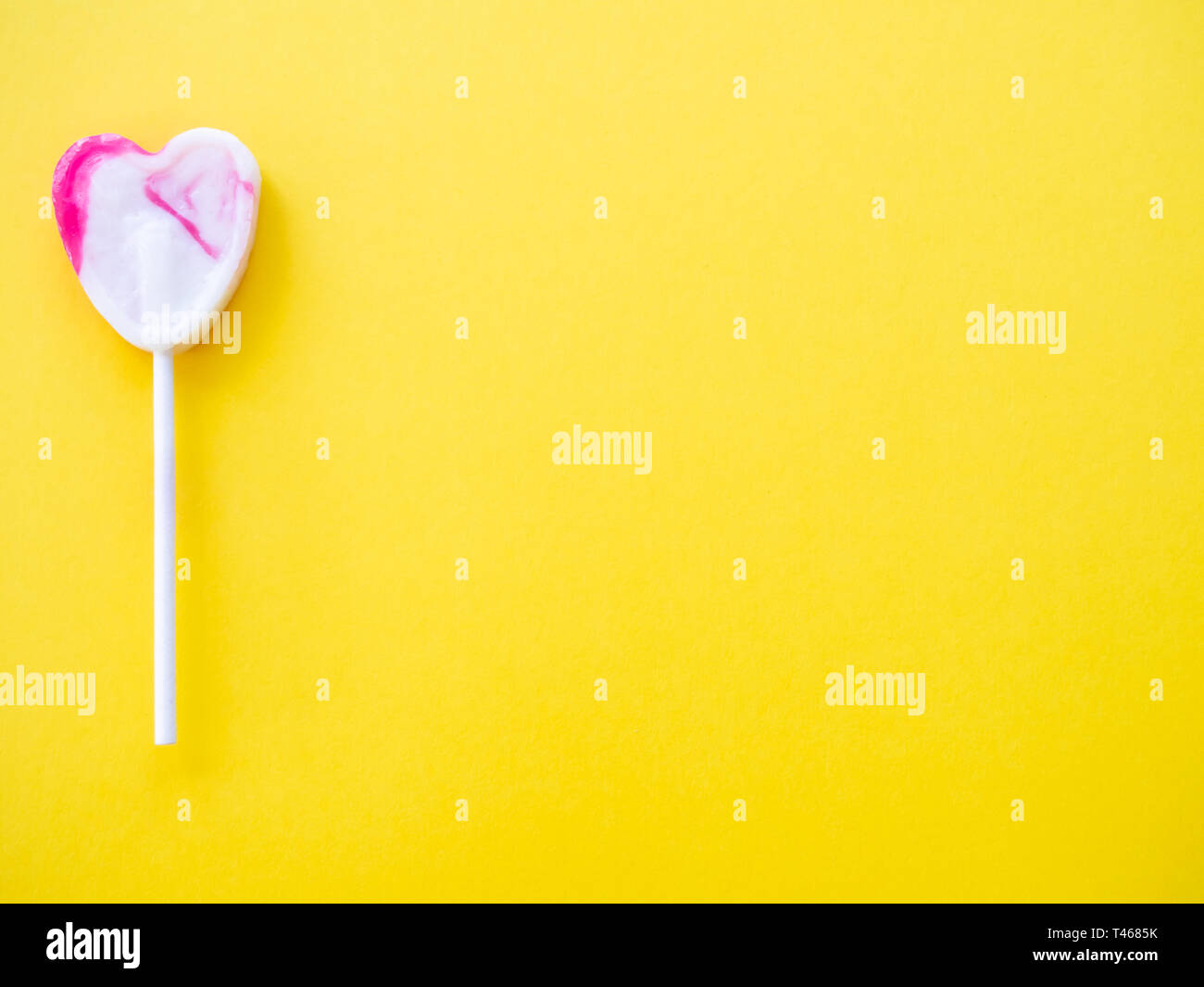 White and pink lollipop on a yellow background Stock Photo