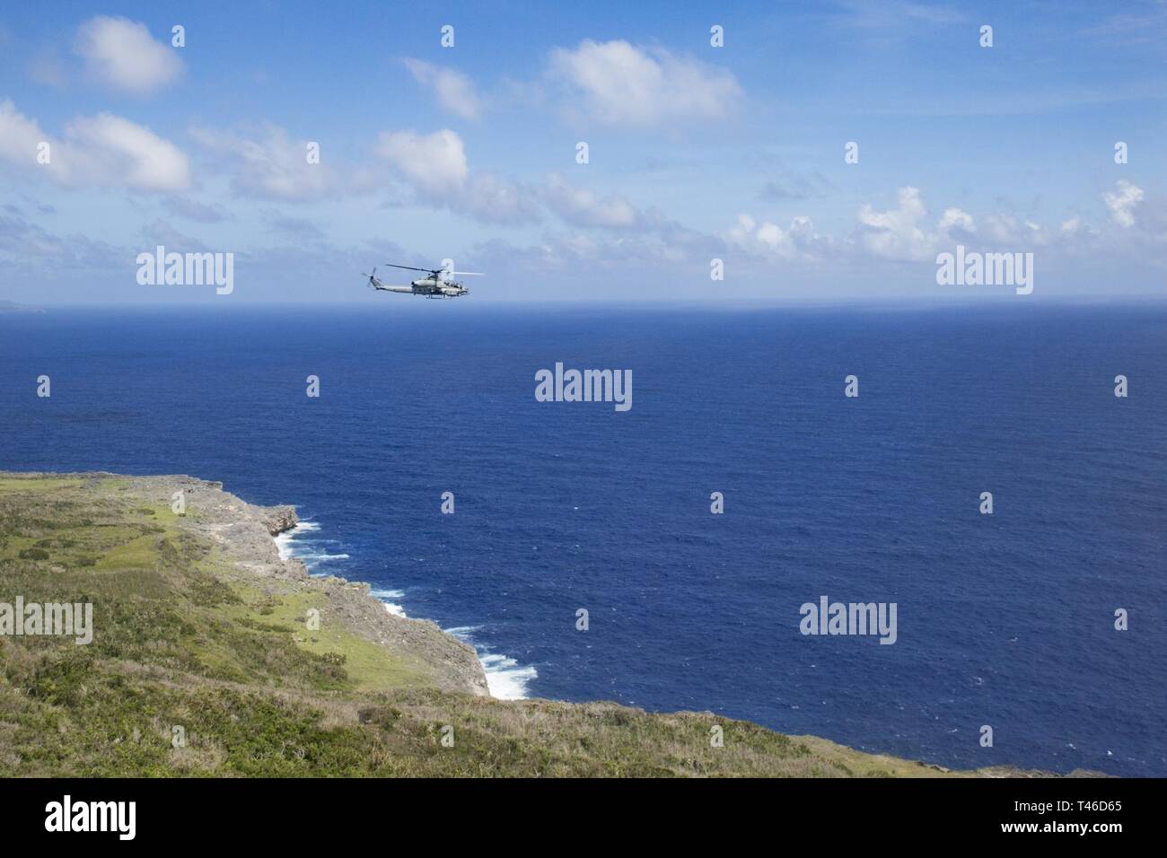 An AH-1Z Viper helicopter belonging to Marine Medium Tiltrotor Squadron 262 (Reinforced) flies toward Tinian, Commonwealth of the Northern Mariana Islands, March 11, 2019. Marines and Sailors with Combat Logistics Battalion 31 led a multi-service task force, partnering with the Federal Emergency Management Agency, to help the U.S. citizens of Tinian begin recovery efforts in the wake of Super Typhoon Yutu last year. The Marines and Sailors, currently participating in two weeks of unit-level training on nearby Guam, visited Tinian to meet with members of the community affected by Yutu in late O Stock Photo
