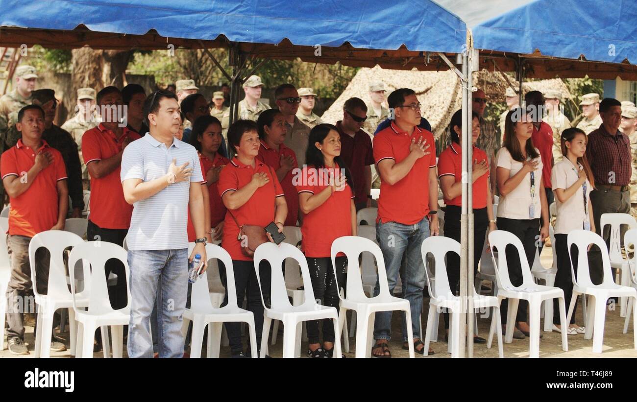 Philippine citizens sing the Philippine National Anthem during the Engineering Civic Action Project 4 opening ceremony at Pagasa Elementary School in Orani, Bataan, as part of Exercise Balikatan, March 12, 2019. During the exercise planning process, military planners visited various locations in coordination with the Armed Forces of the Philippines and local officials to nominate sites. Numerous factors were taken into account, including logistics requirements, unit capabilities, and exercise requirements. Pagasa Elementary School was selected as one of the Balikatan construction projects foll Stock Photo