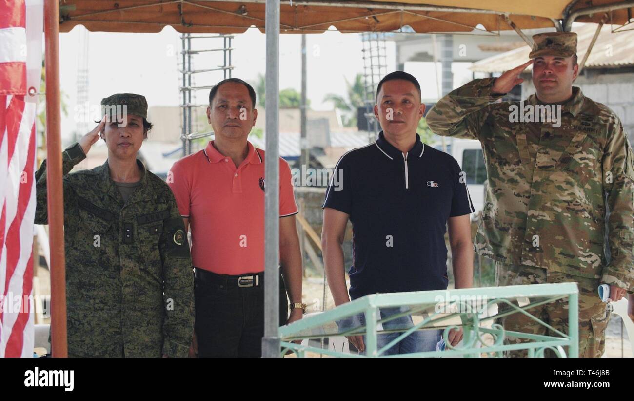 (From left to right) Philippines Army Lt. Col. Francesca Dapiton, Office of the Chief Engineer, Mr. Francisco Bautista, Department of Education district supervisor, the Honorable Efren Pascual Jr., municipal mayor of Orani Bataan, and U.S. Army Lt. Col. Michael Tucker, Combined Joint Civil Military Operations Task Force commander, render respect during the playing of the National Anthem at the Engineering Civic Action Project 4 opening ceremony as part of Exercise Balikatan, March 12, 2019. Exercise Balikatan, in its 35th iteration, is an annual U.S.-Philippine military training exercise focus Stock Photo