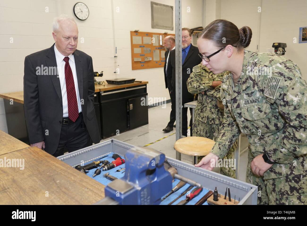 PENSACOLA, Fla. (March 13, 2019) Aviation Structural Mechanic 1st Class Megan Stricklin, right, an instructor at Naval Air Technical Training Center (NATTC), describes how naval aviation maintenance technicians are taught in the metal fabrications lab to Charles Drummond, deputy assistant secretary of defense for education and training in the Office of the Assistant Secretary of Defense for Readiness.  Drummond toured NATTC during a visit to Pensacola that also included Naval Education and Training Command, where he discussed topics such as credentialing; Ready, Relevant Learning; and informat Stock Photo