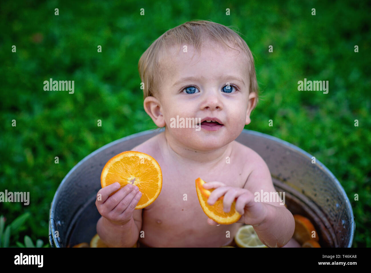 Smiling Baby in bucket with fruit Stock Photo