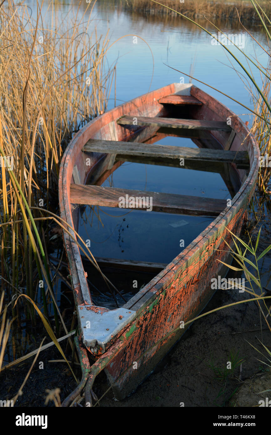 Lonely old wooden fishing boat on autumn lake coast with rain water Stock Photo