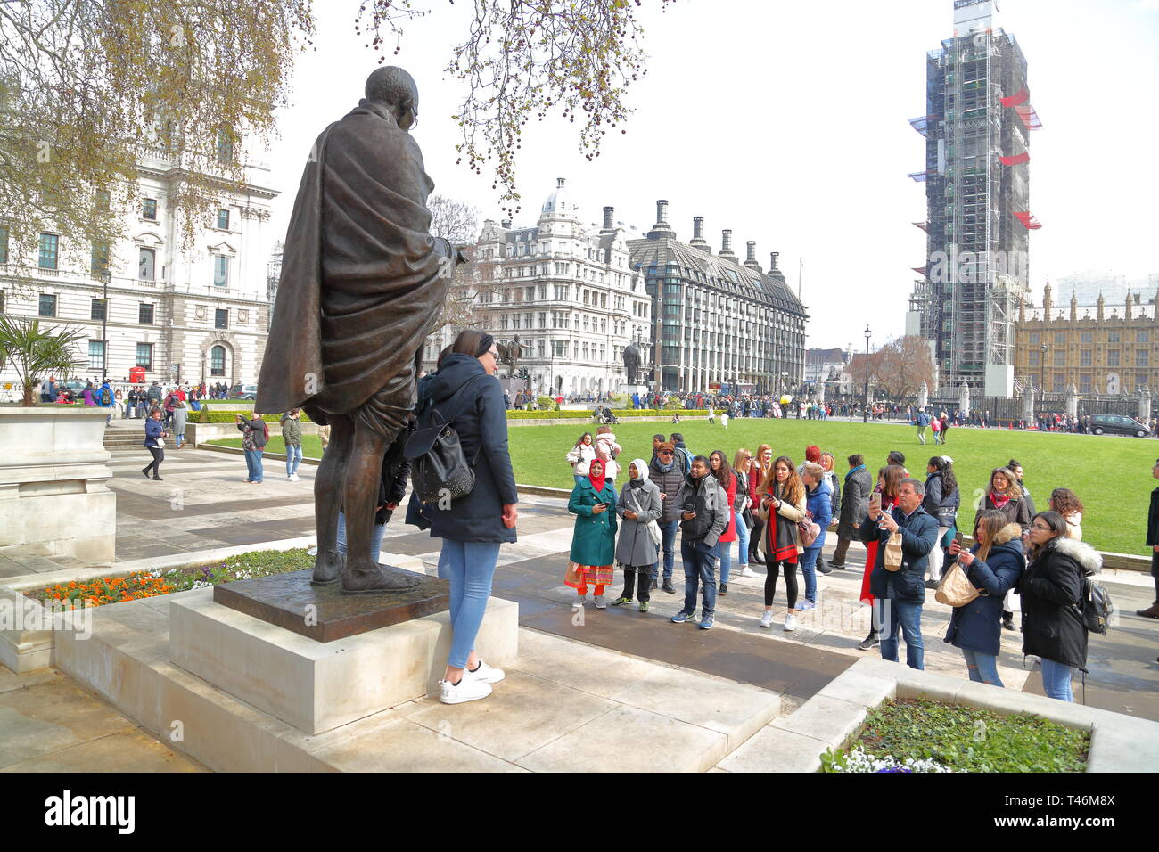 Tourists taking photos with the bronze sculpture of Mahatma Ghandi in the City of Westminster, London, UK Stock Photo