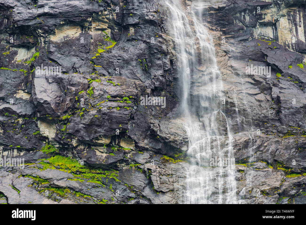 Waterfall on the background of the rock close-up. Rocky textural background with a waterfall. Mountain with a waterfall in Norway. Landscape of Norway Stock Photo