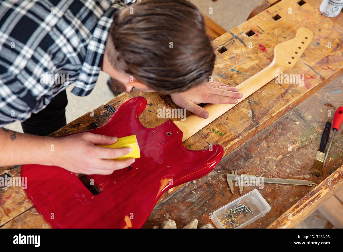 Top view of craftsman sanding a guitar neck in wood at workshop Stock Photo