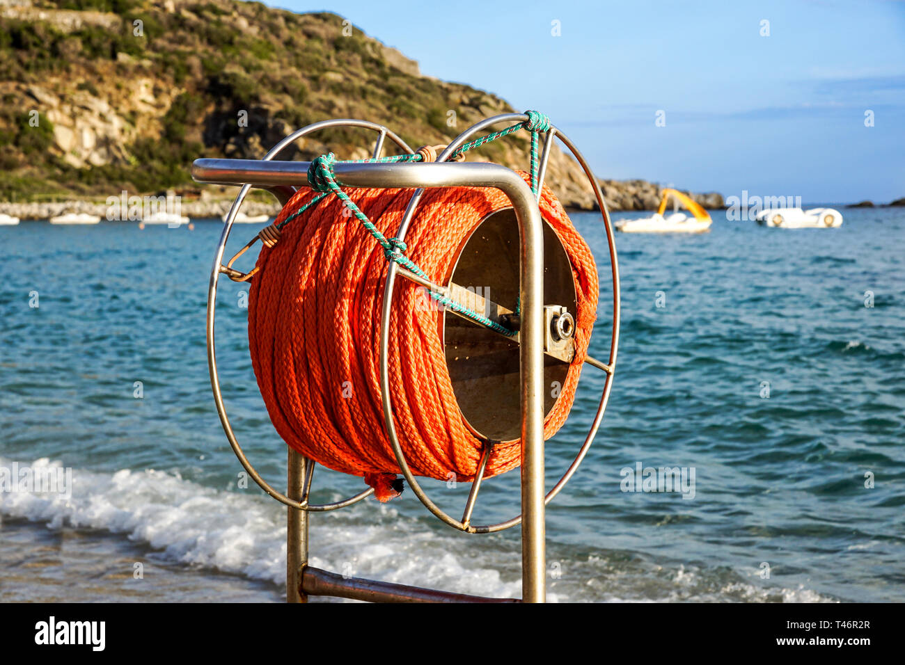 hanging orange life belt with long rope at the beach, security and