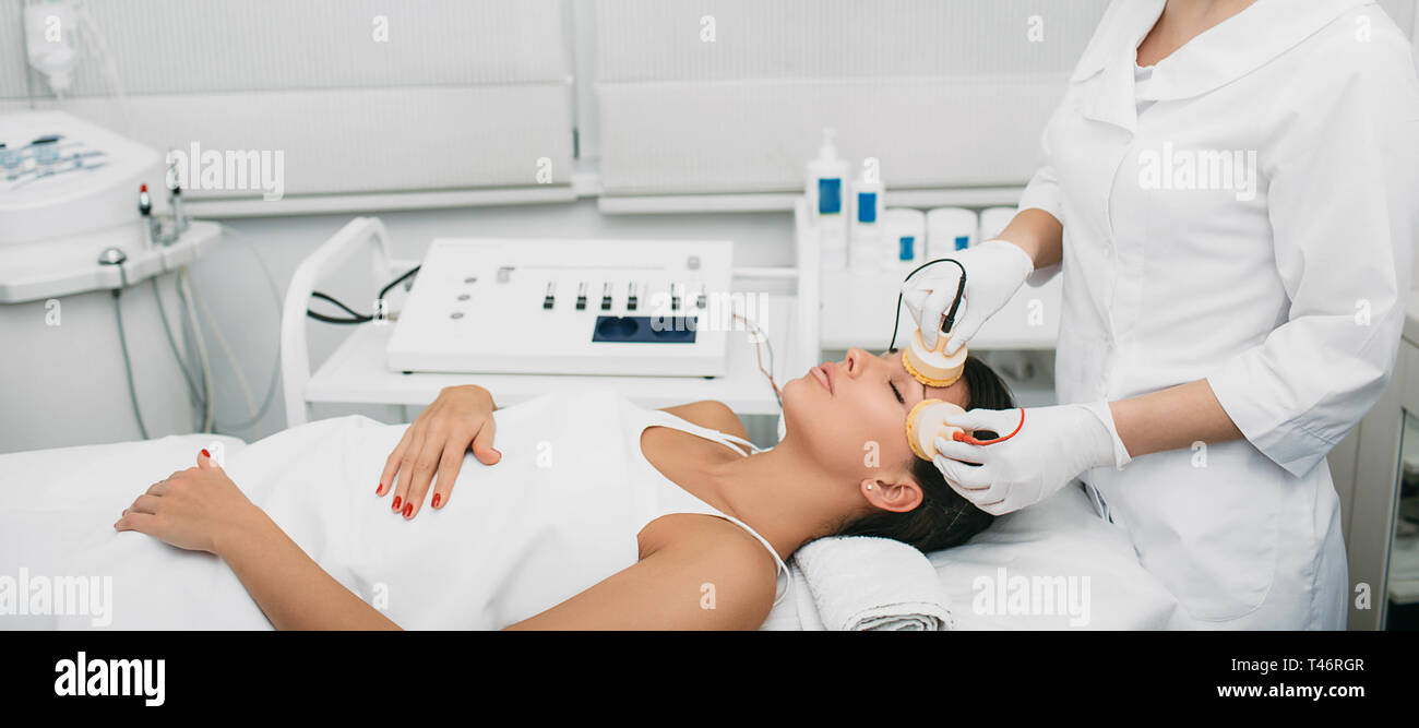 Beautiful woman receiving facial beauty procedure for lifting skin. Stock Photo