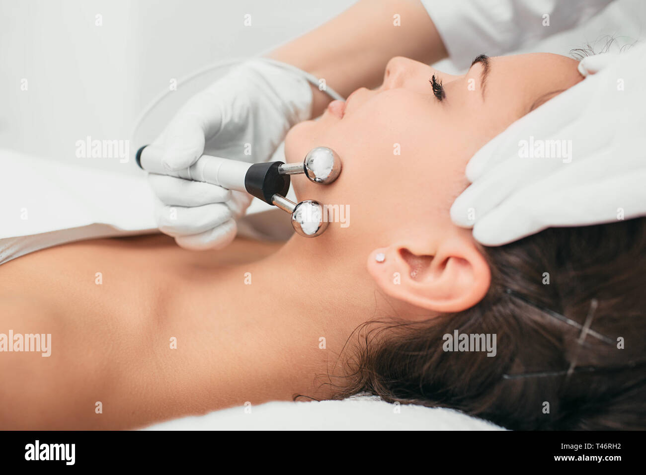 Beautiful woman receiving facial microcurrent procedure for rejuvenation skin. Stock Photo