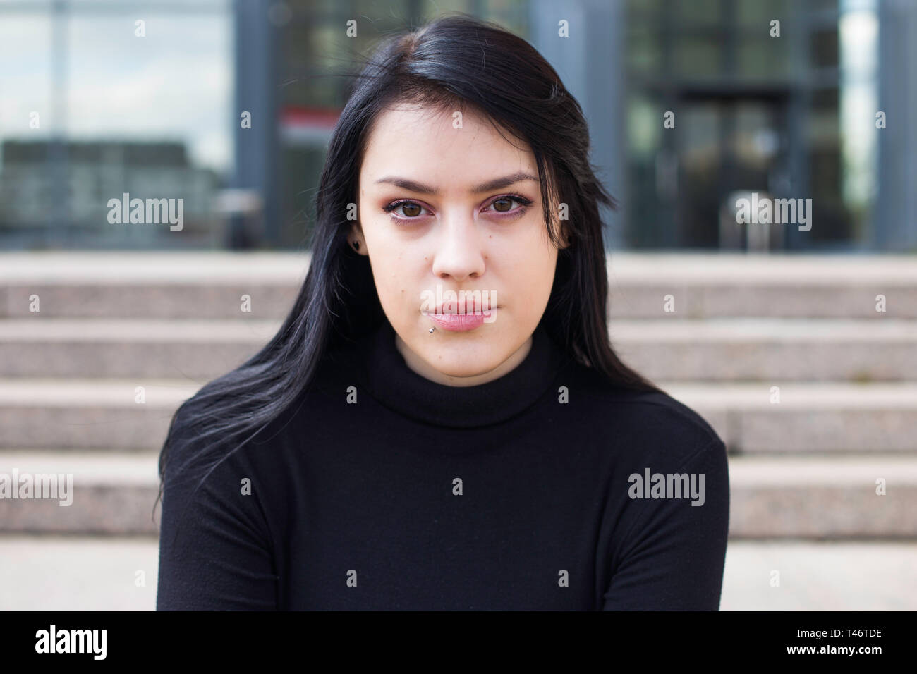 Young business woman in black shirt during the break, sat down on the steps in front of modern building Stock Photo