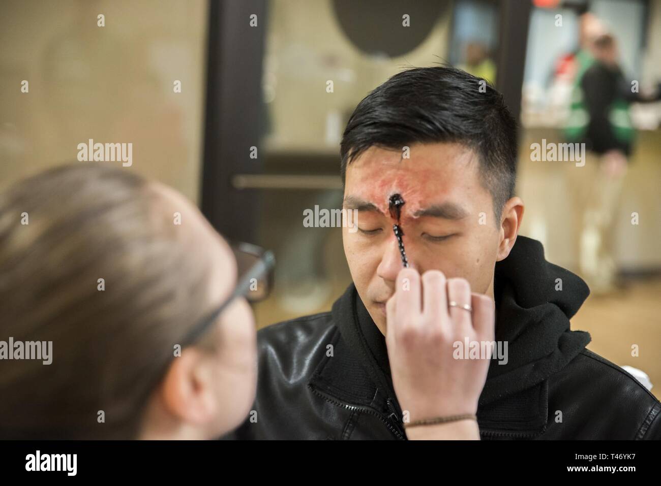 Naval Support Activity Bethesda Sailor personnel Specialist 2nd Class Patrick Caalim has special effects make up applied to simulate a gunshot wound before the start of an active shooter drill March 13, 2019. The practice scenario was part of the Regional Assessment (RASS) of security and emergency services. The inspection is conducted about a year after an installation completes the Command Assessment for Readiness and Training (CART). The final step in the inspection process will be the Final Evaluation Problem (FEP), which will allow base security forces to be certified for 18 months. Stock Photo