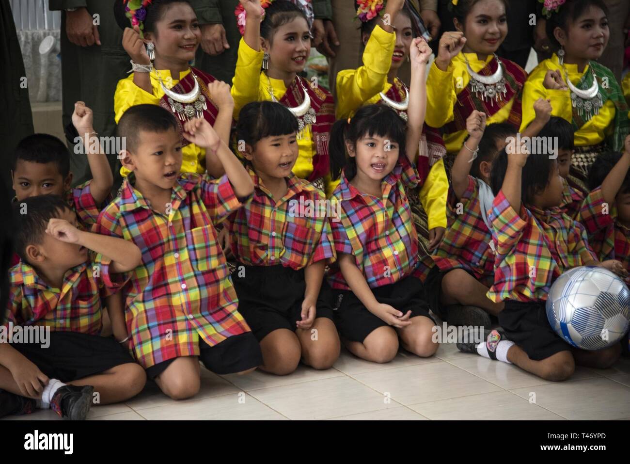 Ban PaLai School children cheer after receiving donations from the U.S., Royal Thai and Singaporean air forces during a COPE Tiger 2019 cultural exchange at Korat, Thailand, March 13, 2019. The school received books, school supplies, sports equipment, and a dish washing system from the three partner nations to support their educational and health needs. Stock Photo