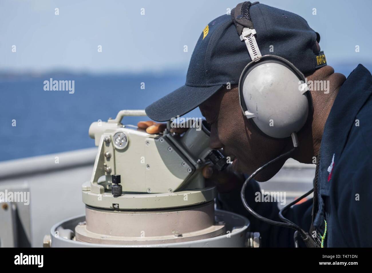 PHILIPPINE SEA (March 14, 2019) Personnel Specialist 1st Class Clement Aribisala tracks the ships bearing using a telescopic alidade as the Avenger-class mine countermeasures ship USS Pioneer (MCM 9) conducts a mine hunting training exercise. Pioneer, part of Mine Countermeasure Squadron 7, is operating in the U.S. 7th Fleet area of operations to enhance interoperability with partners and serve as a ready-response platform for contingency operations. Stock Photo