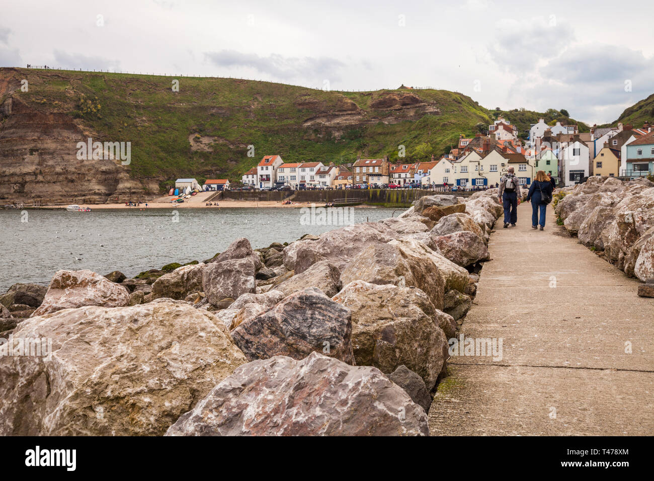 A couple walk along the path leading to the seafront at Staithes,North Yorkshire,England,UK Stock Photo