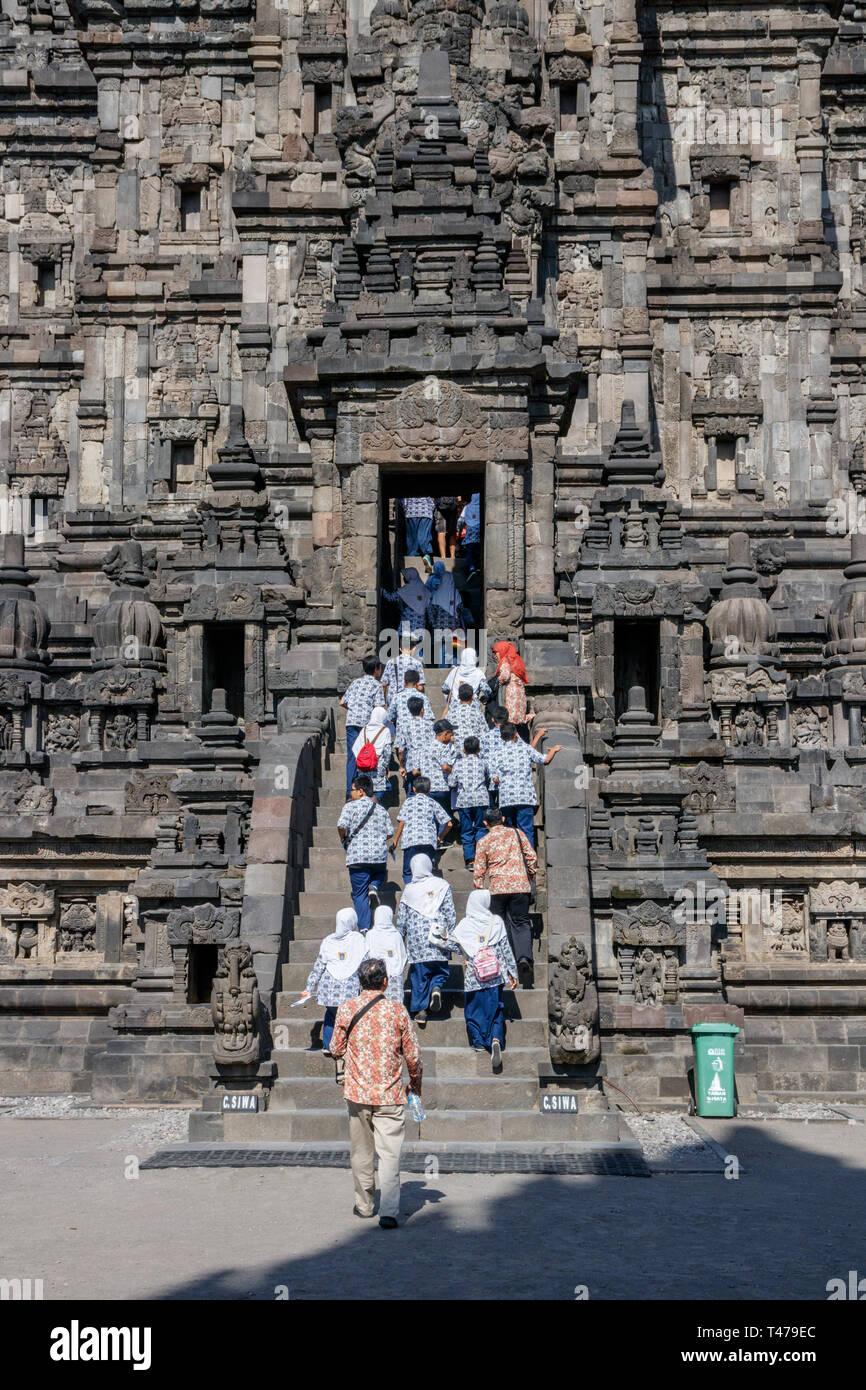 Young school girls, boys and their teachers walking of the stairs of the Vishnu shrine of the Prambanan temple complex on a sunny day. Java, Indonesia Stock Photo