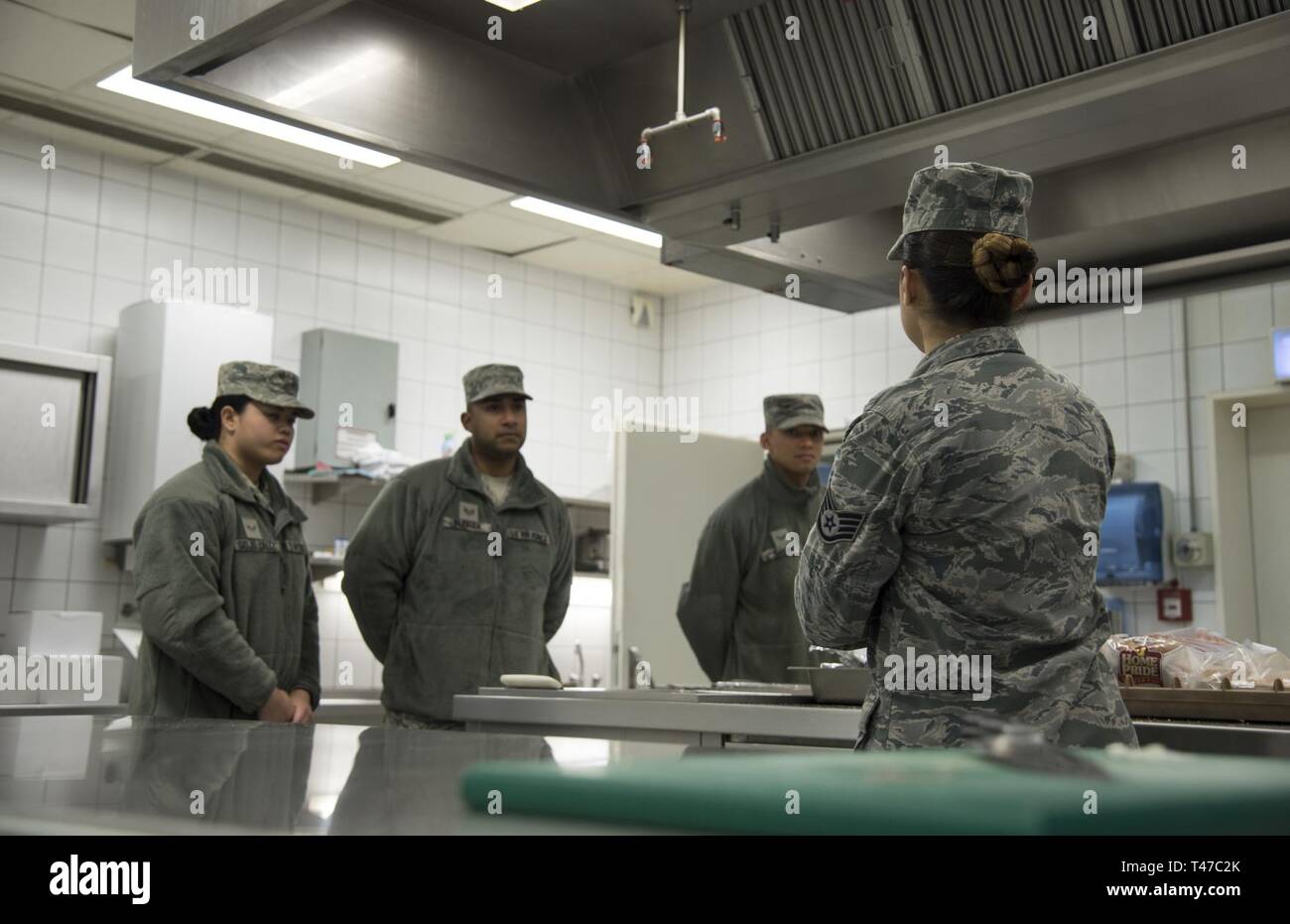 Services specialists of the 108th Wing, listen to instructor, Staff Sgt. Dyan R. Murray, non-commissioned officer in charge of the flight kitchen, 52nd Force Support Squadron, at Spangdahlem Air Base, Germany, Mar. 14, 2019. Murray informed the New Jersey Air National Guardsmen about the operational differences between the flight kitchen and the traditional military dining facility. Members of the 108th Force Support Squadron and 108th Communication Squadron recently spent two weeks training with their active duty counterparts. Stock Photo