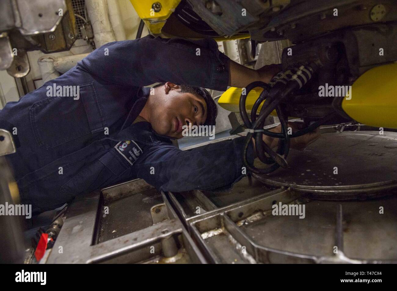 PHILIPPINE SEA (March 15, 2019) Mineman Seaman Carlos Dominguez conducts maintenance on the AN/SQQ 32 Sonar inside the Avenger-class mine countermeasures ship USS Pioneer (MCM 9) as the ship completes a mine hunting training exercise. Pioneer, part of Mine Countermeasure Squadron 7, is operating in the U.S. 7th Fleet area of operations to enhance interoperability with partners and serve as a ready-response platform for contingency operations. Stock Photo
