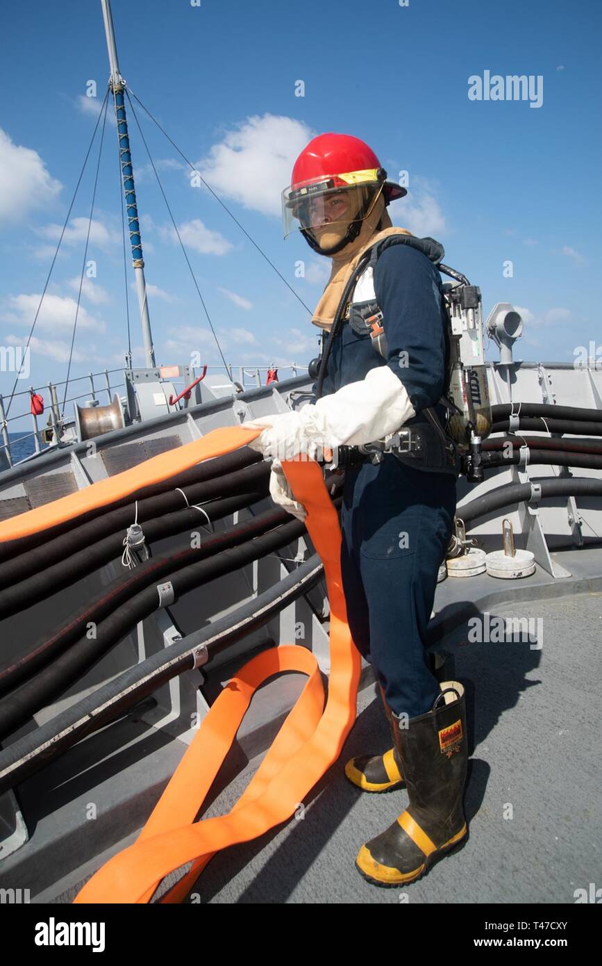 SOUTH CHINA SEA (March 15, 2019) Mineman Seaman Logan Hardy, from Millbrook, Alabama, prepares a firehose during a general quarters drill aboard the Avenger-class mine countermeasures ship USS Chief (MCM 14). Chief, part of Mine Countermeasure Squadron 7, is operating in the Indo-Pacific region to enhance interoperability with partners and serve as a ready-response platform for contingency operations. Stock Photo