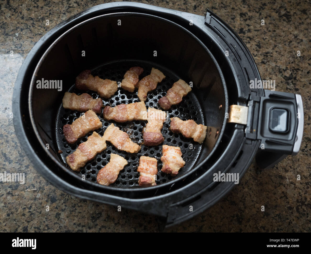 Pork Belly cooking in an air fryer basket Stock Photo