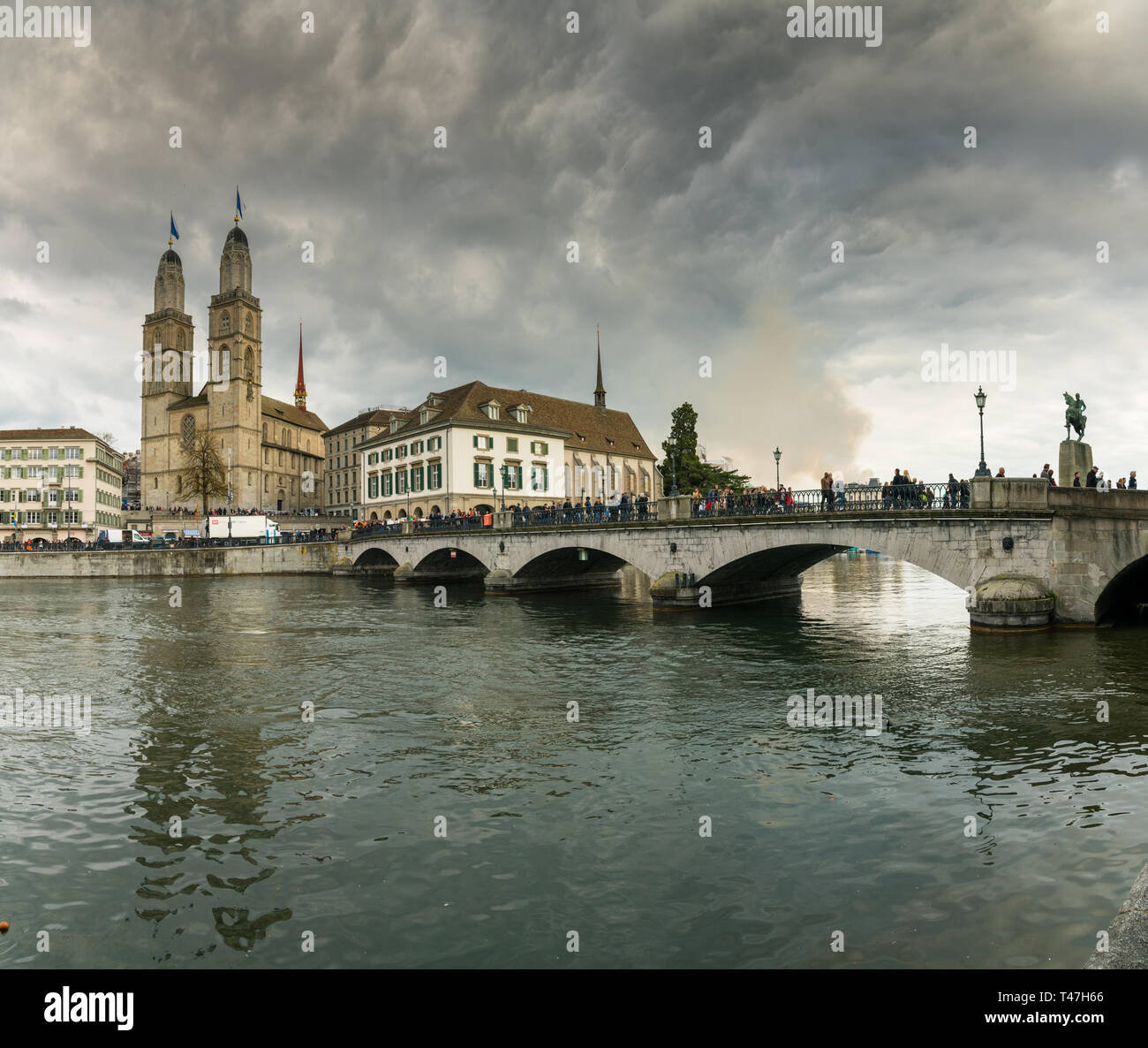 Zurich, ZH / Switzerland - April 8, 2019: Zurich cityscape with many people crossing the river Limmat during the traditional spring festival of Sechse Stock Photo