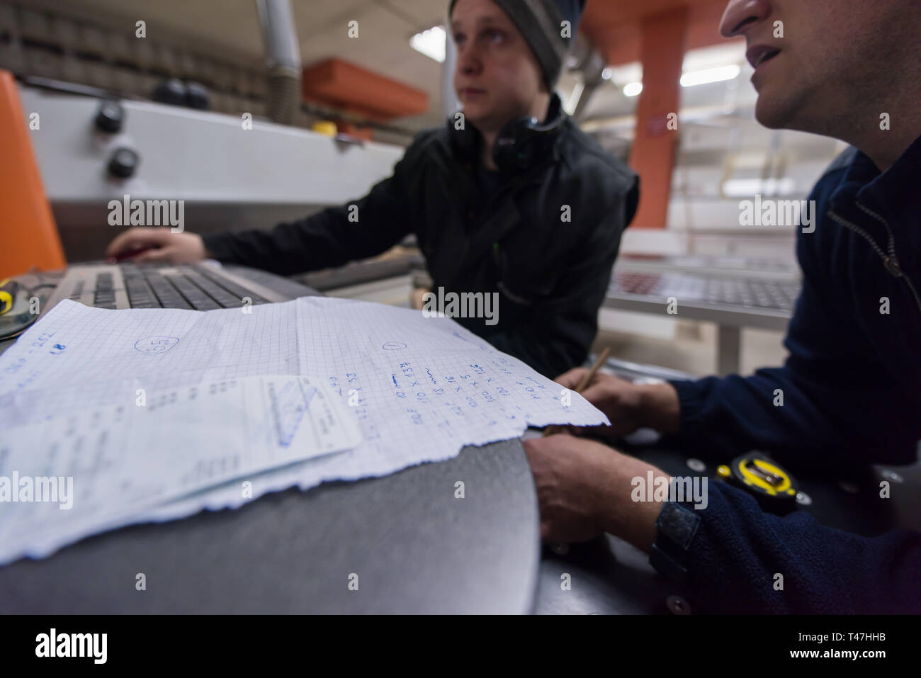 two young carpenters calculating and programming a cnc wood working machine in workshop. wood workers preparing a computer program for CNC machine at  Stock Photo